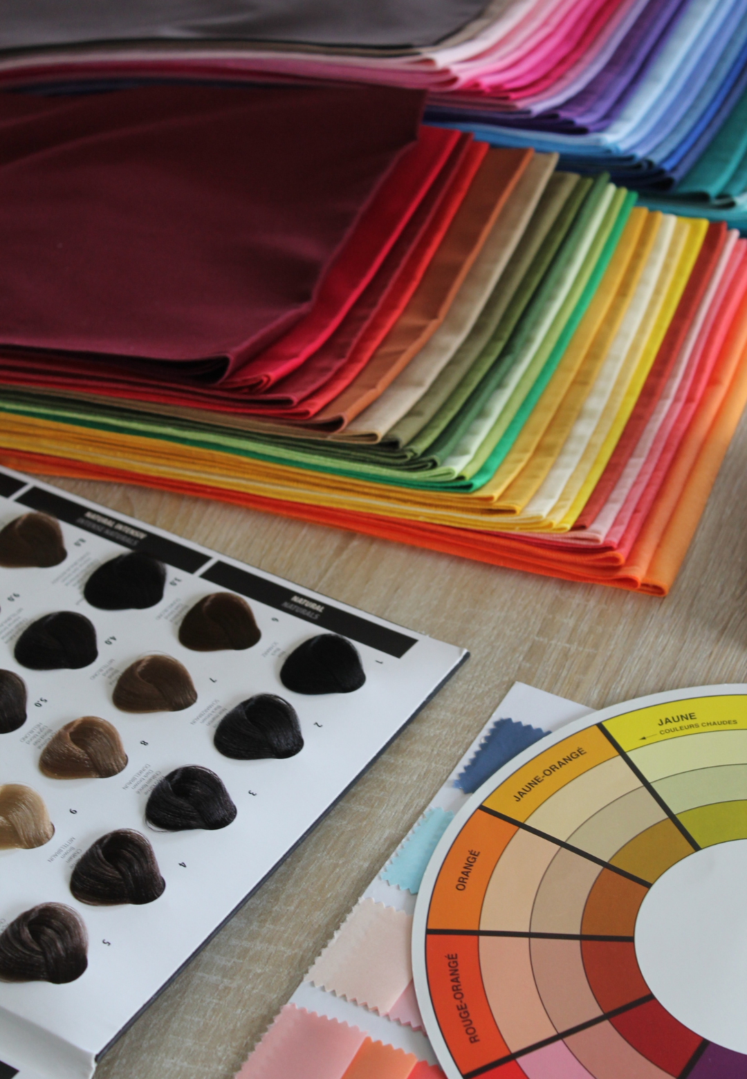 Outils de visagisme utilisés dans le cadre d’un coaching en image à Nice Coaching en image à Nice – Atelier de visagisme avec miroir, étoffes colorées, mèches capillaires et roue chromatique