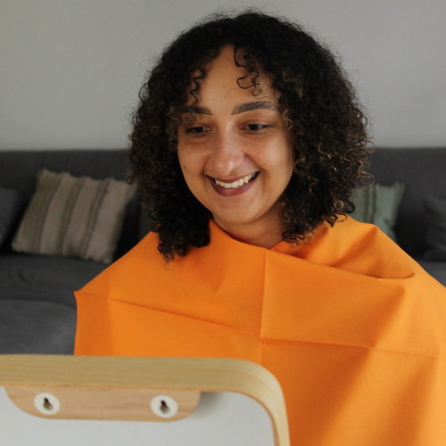 Séance d’analyse colorimétrique à Nice – coaching en image personnalisé avec drapping Femme souriante face au miroir pendant une analyse colorimétrique à Nice avec étoffe apposée par une coach en image